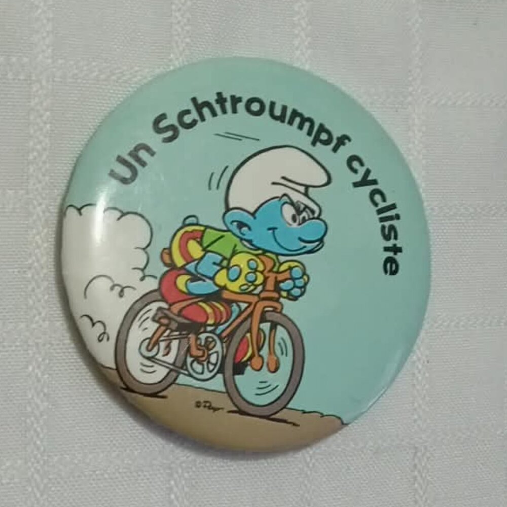 Strange & unusual vintage button pin featuring "un schtroumphf cycliste"